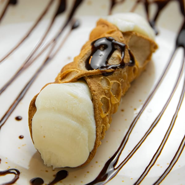 A Scarpino's Classic Italian cannoli, filled with creamy white ricotta and drizzled with chocolate sauce.