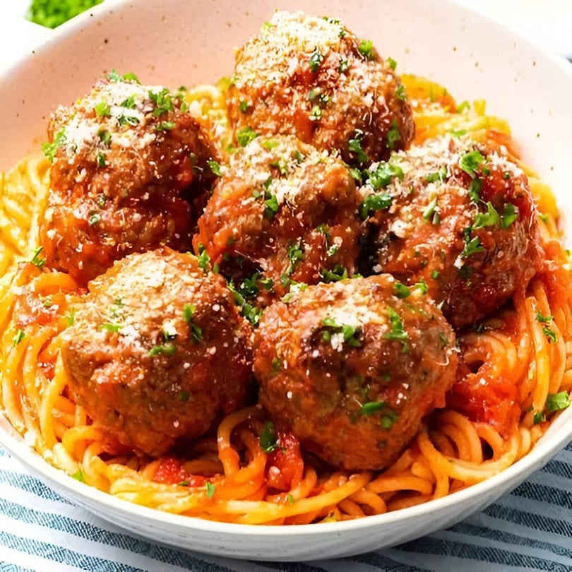 Scarpino's spaghetti and meatballs, topped with parmesan cheese and fresh parsley in a white bowl.